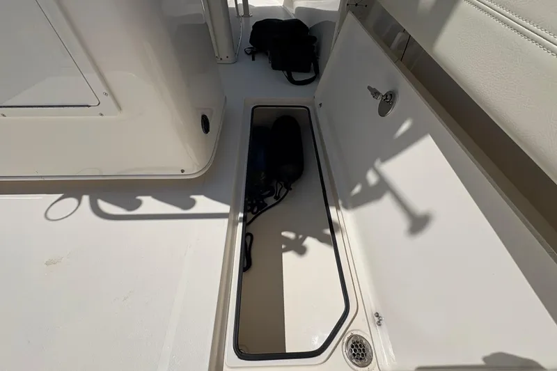 Slide: The Image of 2018 Cobia 277 Center Console boat storage compartment with open hatch and visible equipment. - 19