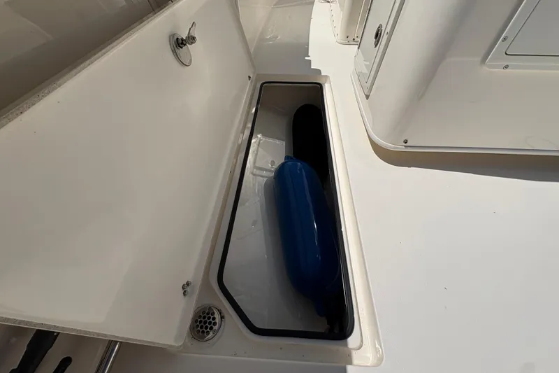 Slide: The Image of Storage compartment on a 2018 Cobia 277 Center Console boat with blue fender. - 20
