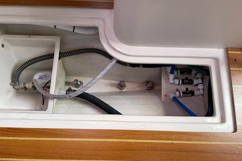 Slide: The Image of Interior view of a 2014 Catalina 355 sailboat's plumbing system with visible hoses and fittings. - 25