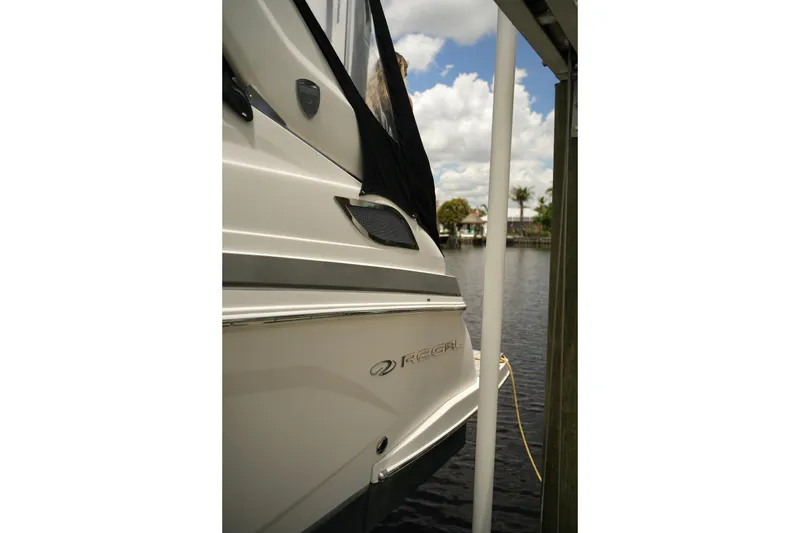 Slide: The Image of 2018 Regal 28 Express boat docked by a serene waterfront under a cloudy sky. - 2