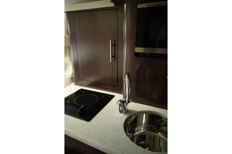 Slide: The Image of Interior of 2018 Regal 28 Express boat featuring a sleek kitchenette with sink and stovetop. - 37