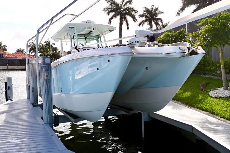 The Image of 2023 World Cat 325 CC boat docked, surrounded by tropical scenery and palm trees. - 0