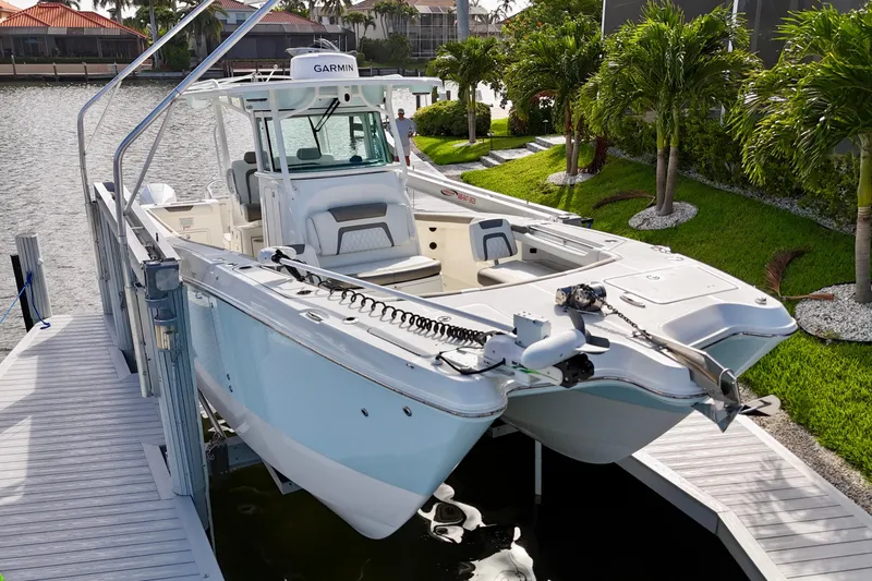 Slide: The Image of 2023 World Cat 325 CC boat docked near lush greenery and waterfront homes. - 3