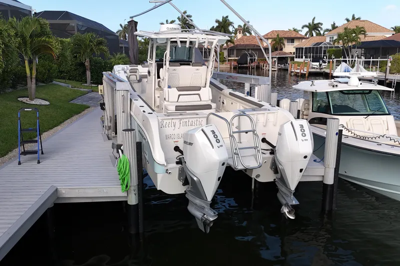 Slide: The Image of 2023 World Cat 325 CC boat docked with twin 300 V8 engines, surrounded by lush greenery. - 6
