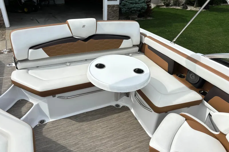 Slide: The Image of 2020 Four Winns HD220 boat interior with white and brown seating, round table, and cup holders. - 19