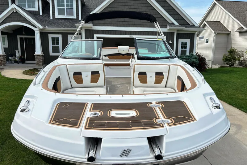 Slide: The Image of 2020 Four Winns HD220 boat parked in front of a suburban house. - 6