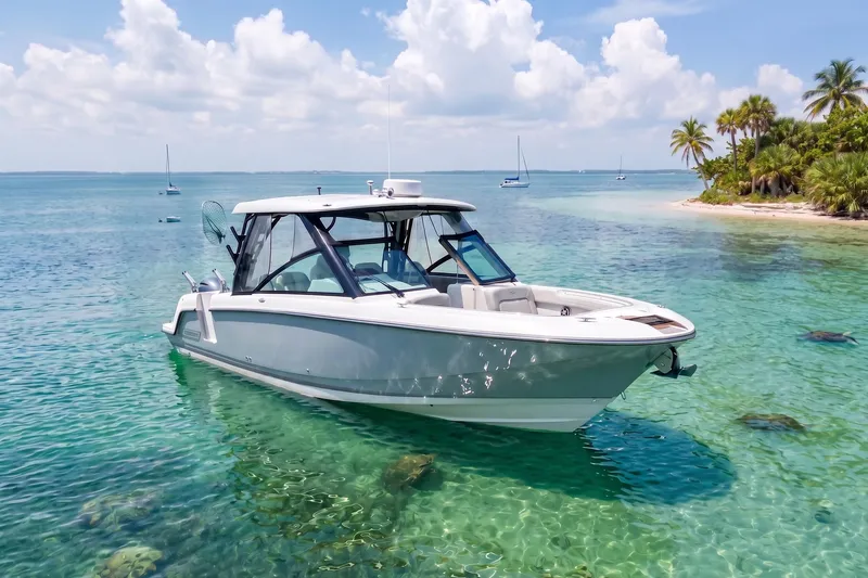 The Image of 2024 Boston Whaler 320 Vantage boat in clear tropical waters near a palm-lined shore. - 0