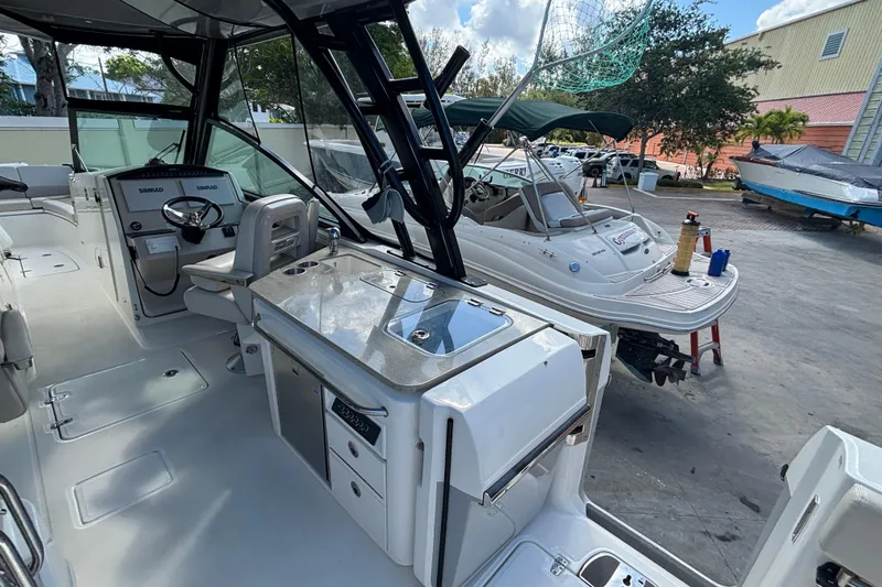 Slide: The Image of 2024 Boston Whaler 320 Vantage interior with helm and seating area, docked outdoors. - 5