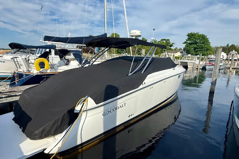 Slide: The Image of 2007 Cobalt 323 boat docked with black cover and canopy in a marina. - 22