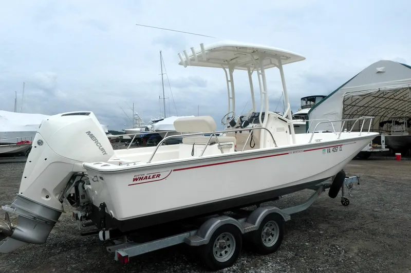 Slide: The Image of 2023 Boston Whaler 210 Montauk boat on trailer, featuring Mercury outboard engine. - 2