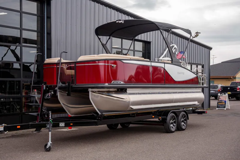 Slide: The Image of 2026 Harris Sunliner 230 pontoon boat on trailer, parked outside a building. - 10
