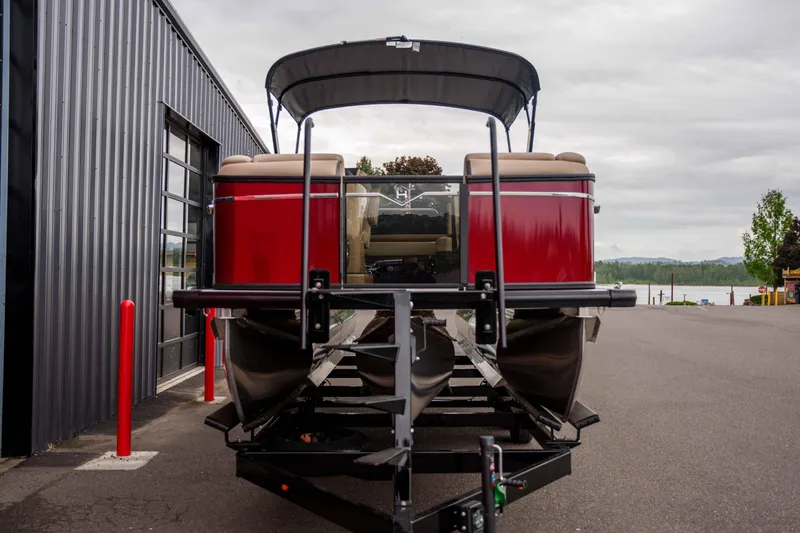 Slide: The Image of 2026 Harris Sunliner 230 pontoon boat on trailer, parked near a modern building. - 11