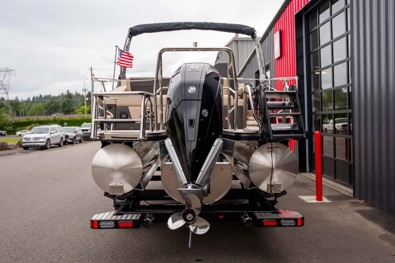 Slide: The Image of 2026 Harris Sunliner 230 pontoon boat with outboard motor, parked near a building. - 18