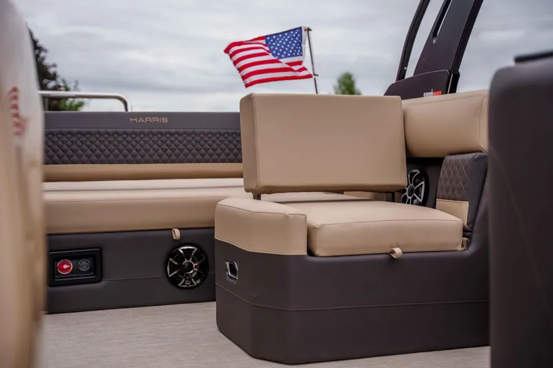 Slide: The Image of 2026 Harris Sunliner 230 boat interior with beige seating and American flag in background. - 27
