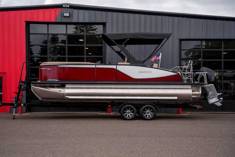 The Image of 2026 Harris Sunliner 230 pontoon boat on trailer, parked outside a modern building. - 9