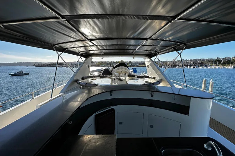 Slide: The Image of Monte Fino 92 yacht deck view, 1996 model, with canopy and scenic harbor backdrop. - 56