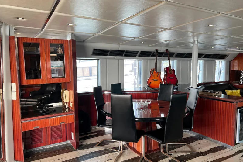 Slide: The Image of Luxurious Monte Fino 92 yacht interior with dining area, guitars, and elegant wood finishes, 1996 model. - 93