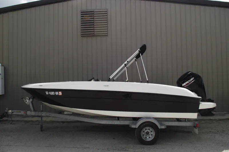 The Image of 2021 Bayliner Element E18 boat on trailer, parked beside a building. - 0