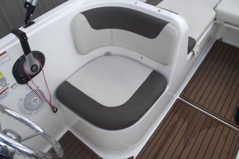 Slide: The Image of 2021 Bayliner Element E18 boat interior with cushioned seating and wood-style flooring. - 18