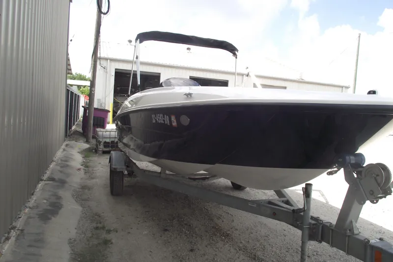 Slide: The Image of 2021 Bayliner Element E18 boat on trailer near a metal building. - 2