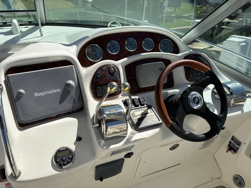 Slide: The Image of The image shows the helm of a 2006 Sea Ray Sundancer 320 with wood trim and modern instruments. - 9
