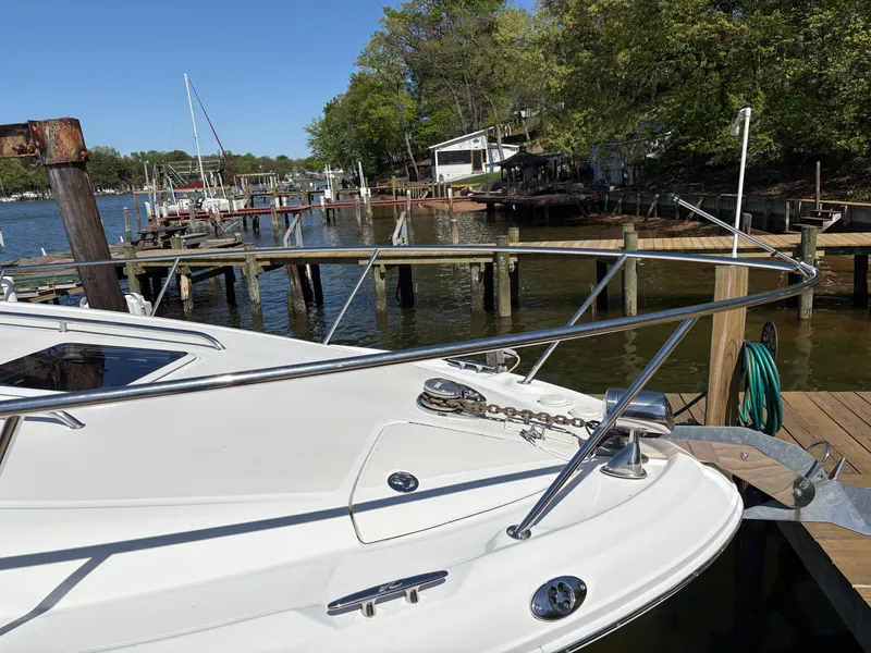 Slide: The Image of A 2006 Sea Ray Sundancer 320 docked at a wooden pier. Trees and other boats are visible in the background. - 2