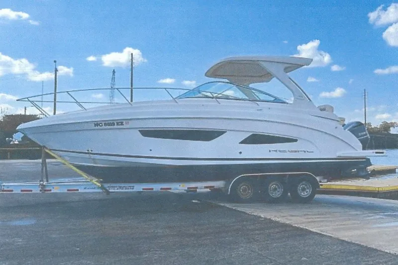 The Image of 2020 Regal 33 XO boat on trailer under blue sky. - 1