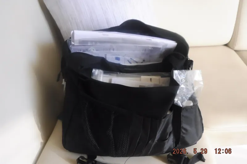Slide: The Image of Open black bag on a white couch containing documents and plastic bags. - 45