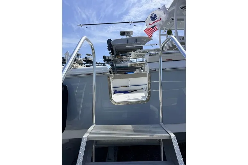 Slide: The Image of 2026 Sea Hunt Gamefish 30 Coffin Box boat with ladder and flags under blue sky. - 27