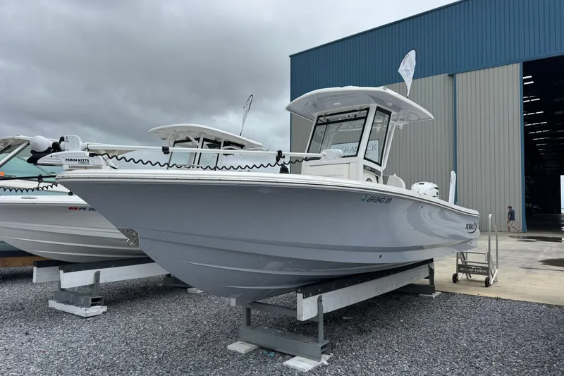 The Image of 2023 Robalo 266 Cayman boat displayed outside a large warehouse. - 1