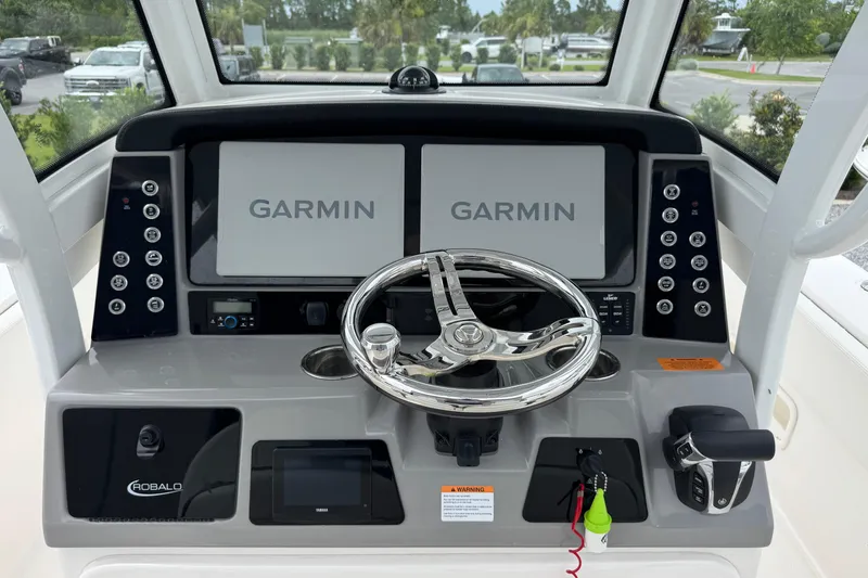 Slide: The Image of 2023 Robalo 266 Cayman boat dashboard with dual Garmin displays and steering wheel. - 16