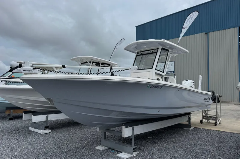 Slide: The Image of 2023 Robalo 266 Cayman boat displayed outdoors near a marine service building. - 8