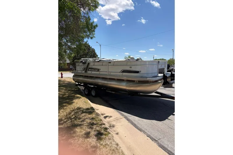 Slide: The Image of 2026 Starcraft EX 22 FD4 pontoon boat on trailer under clear blue sky. - 2