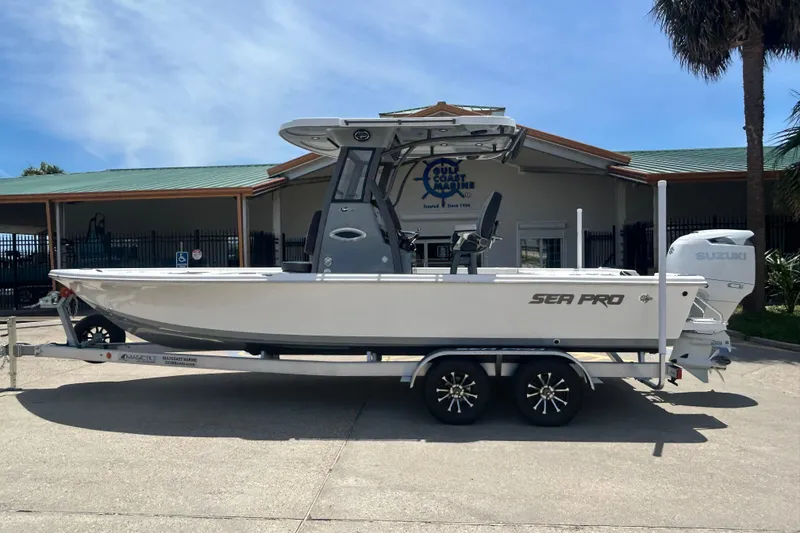 The Image of 2026 Sea Pro 250 Bay boat on trailer, parked outside a marine dealership. - 0