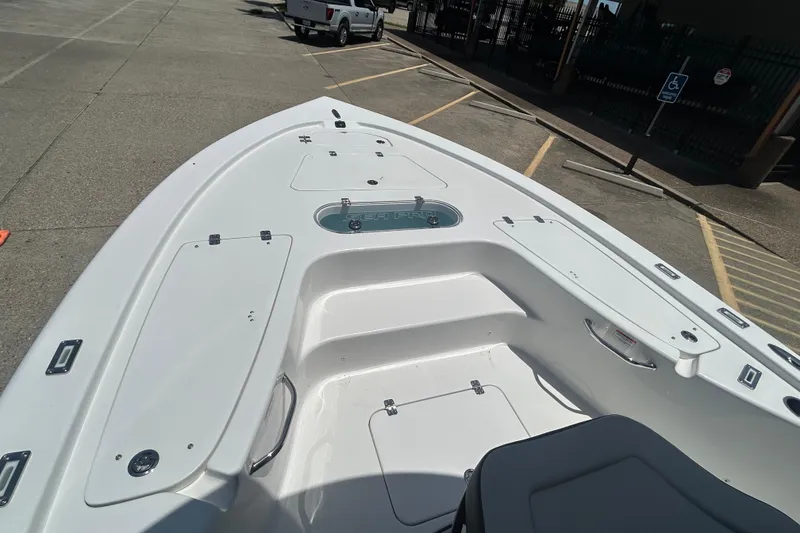 Slide: The Image of 2026 Sea Pro 250 Bay boat interior with storage compartments and seating, parked in a lot. - 12