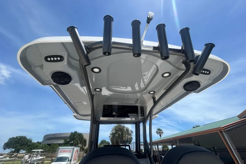 Slide: The Image of 2026 Sea Pro 250 Bay boat T-top with rod holders and speakers under a clear sky. - 16