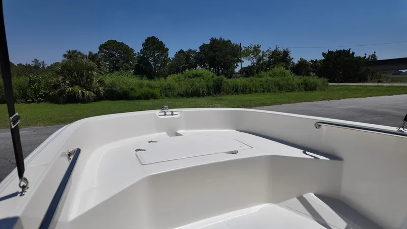 Slide: The Image of The image shows the bow of a 2027 Boston Whaler 160 Super Sport boat. It features a clean, open white deck with railings. Trees and a clear sky are visible in the background. - 8