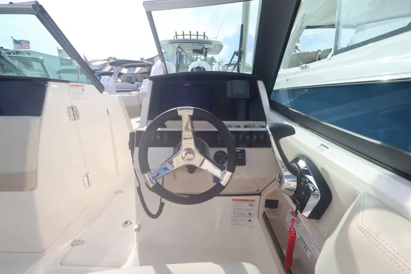 Slide: The Image of The cockpit of a 2027 Boston Whaler 240 Vantage with a modern steering wheel and instruments. - 23