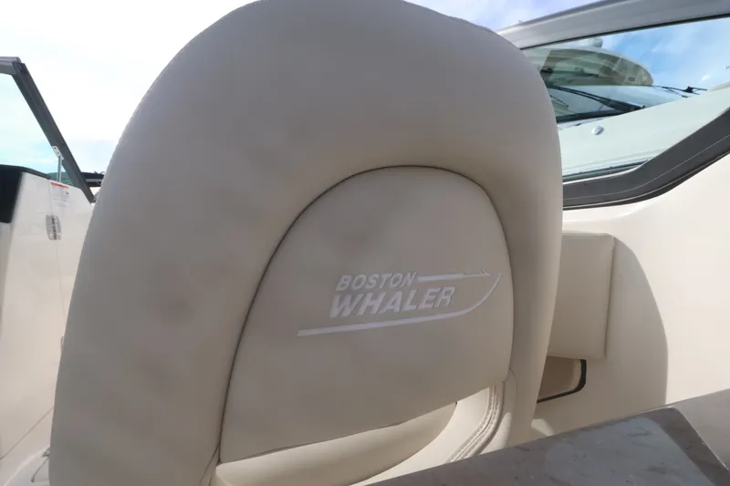 Slide: The Image of Close-up of a Boston Whaler 240 Vantage seat with logo, surrounded by light upholstery. - 22