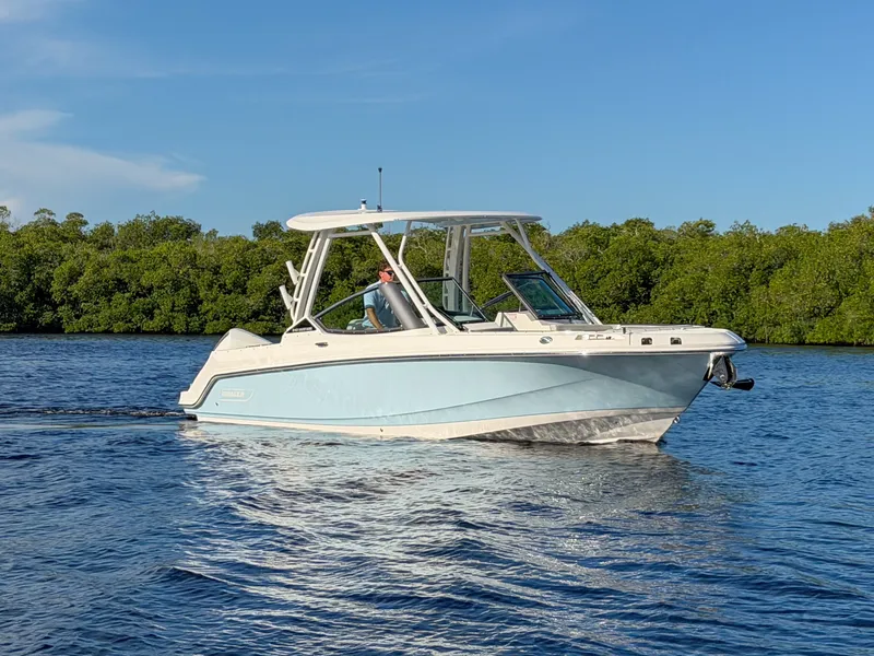 Slide: The Image of A 2027 Boston Whaler 240 Vantage cruising on calm water with green shoreline in the background. - 22