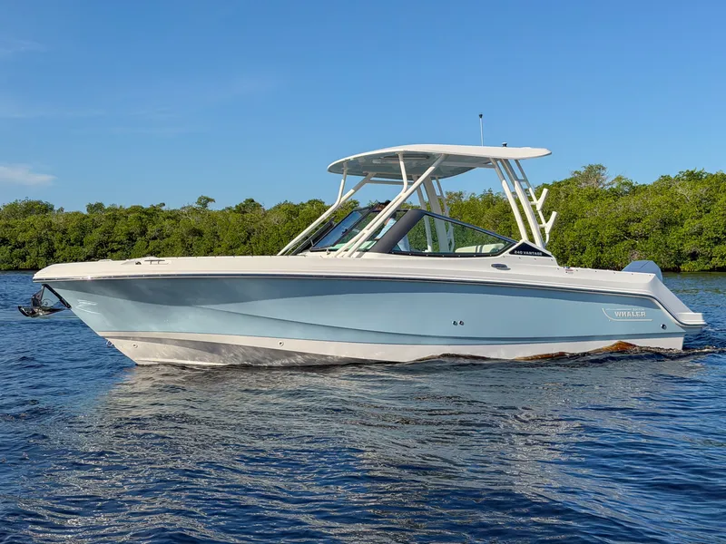 Slide: The Image of A 2027 Boston Whaler 240 Vantage on calm water with a blue sky in the background. - 25