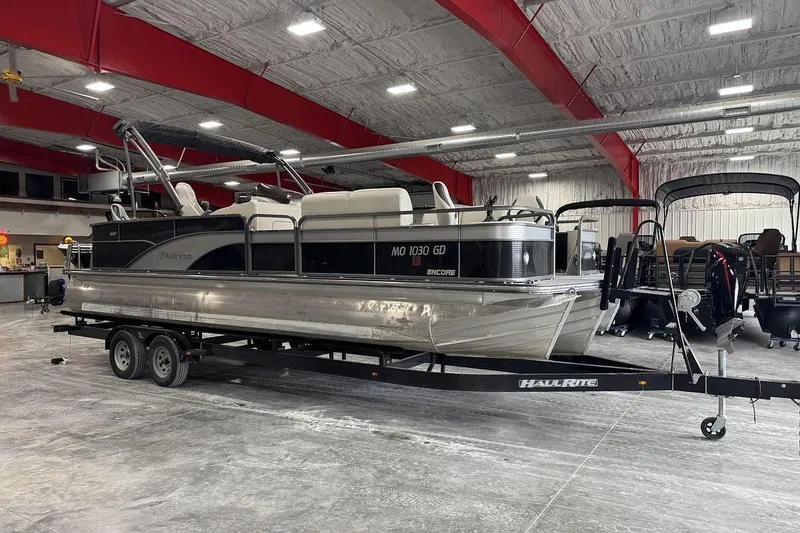The Image of 2016 Manitou 24 Aurora LE Angler pontoon boat on trailer in indoor showroom. - 0