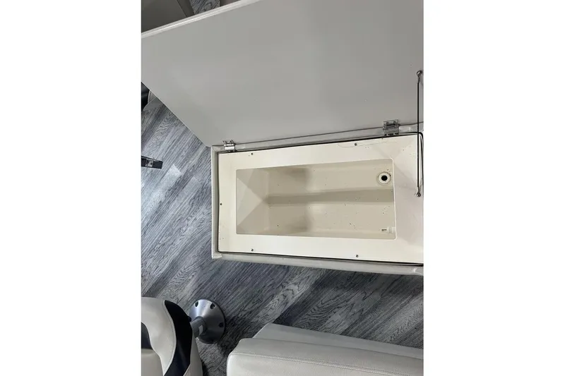 Slide: The Image of Open storage compartment on 2016 Manitou 24 Aurora LE Angler boat, featuring a clean interior. - 10