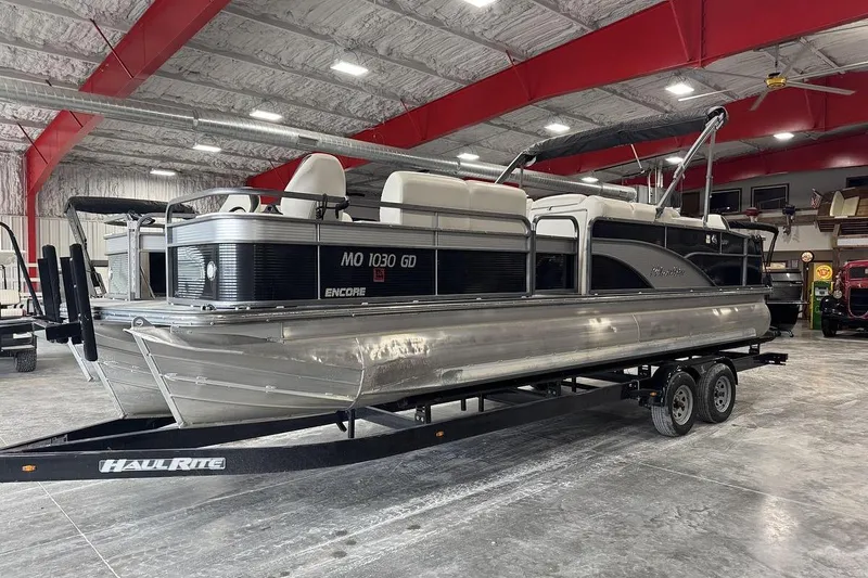 Slide: The Image of 2016 Manitou 24 Aurora LE Angler pontoon boat on trailer in indoor storage facility. - 2