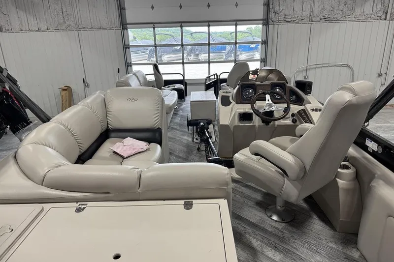 Slide: The Image of 2016 Manitou 24 Aurora LE Angler interior with beige seating and steering console. - 6