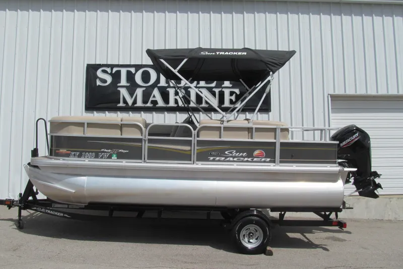 The Image of 2023 Sun Tracker Party Barge 18 DLX pontoon boat on trailer, displayed at dealership. - 1