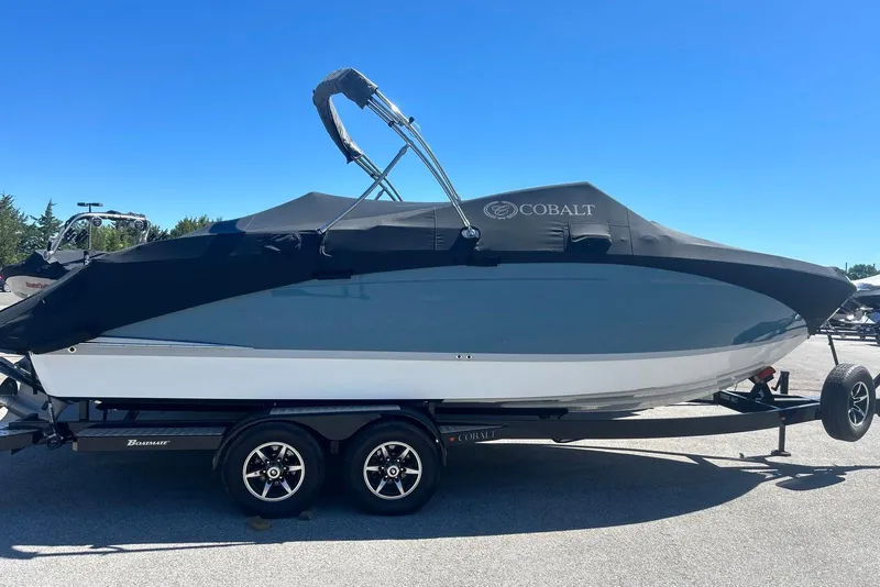 Slide: The Image of 2021 Cobalt R6 boat on trailer with cover, parked outdoors under clear blue sky. - 1