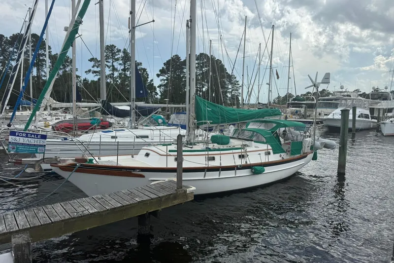 The Image of 1989 Cabo Rico 34 sailboat docked, featuring green covers, for sale at a marina. - 0