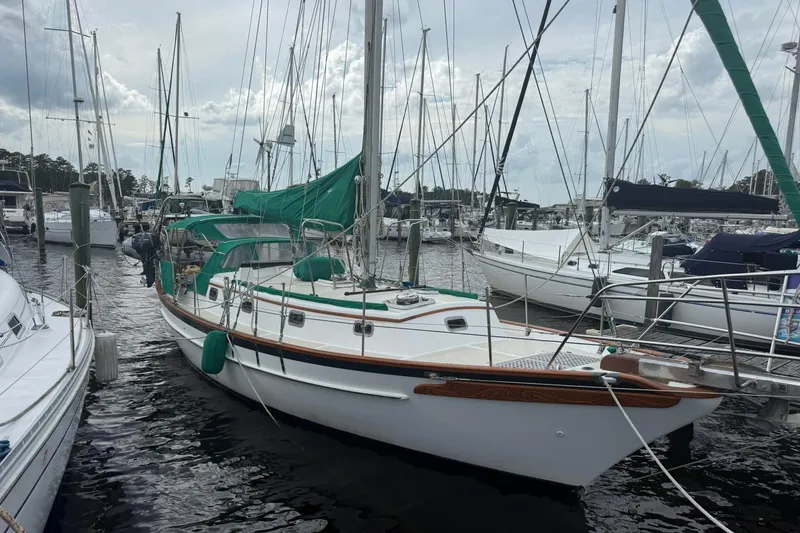 Slide: The Image of 1989 Cabo Rico 34 sailboat docked at marina with green sail cover. - 1