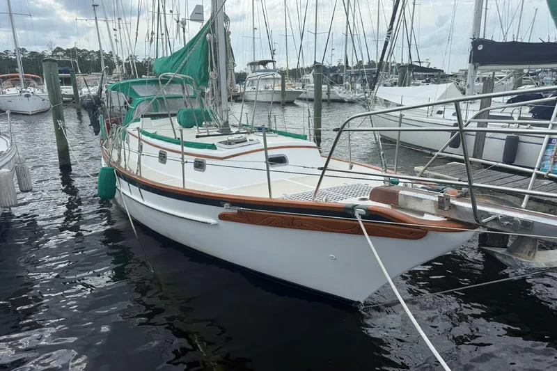 Slide: The Image of 1989 Cabo Rico 34 sailboat docked in marina, featuring green sail cover and wooden accents. - 2